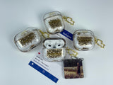 Clear earbud case filled with golden brown liquid glitter, attached to a gold cat-shaped clip and a miniature vinyl record keychain.