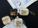 Clear earbud case filled with golden brown liquid glitter, attached to a gold cat-shaped clip and a miniature vinyl record keychain.