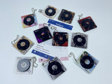 A collection of 11 square acrylic keychains featuring spinning miniature vinyl records and different aesthetic album artwork on a white background.