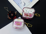 Clear earbud case filled with red and pink liquid glitter, attached to a gold cat-shaped clip and a miniature vinyl record keychain.