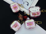 Clear earbud case filled with red and pink liquid glitter, attached to a gold cat-shaped clip and a miniature vinyl record keychain.