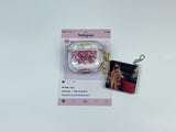 Clear earbud case filled with red and pink liquid glitter, attached to a gold cat-shaped clip and a miniature vinyl record keychain.