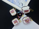 Clear earbud case filled with pink liquid glitter, attached to a gold cat-shaped clip and a miniature vinyl record keychain.
