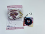 Clear earbud case filled with pink liquid glitter, attached to a gold cat-shaped clip and a miniature vinyl record keychain.