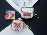 Clear earbud case filled with pink liquid glitter, attached to a gold cat-shaped clip and a miniature vinyl record keychain.