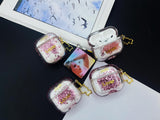 Clear earbud case filled with pink liquid glitter, attached to a gold cat-shaped clip and a miniature vinyl record keychain.