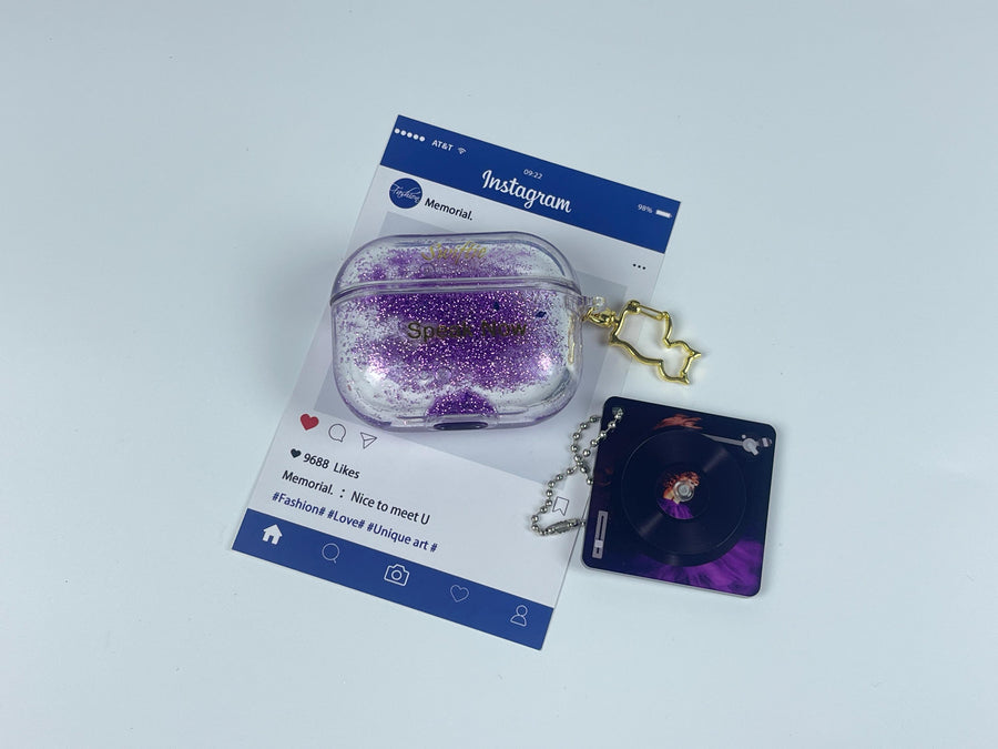 Clear earbud case filled with royal purple liquid glitter, attached to a gold cat-shaped clip and a miniature vinyl record keychain.