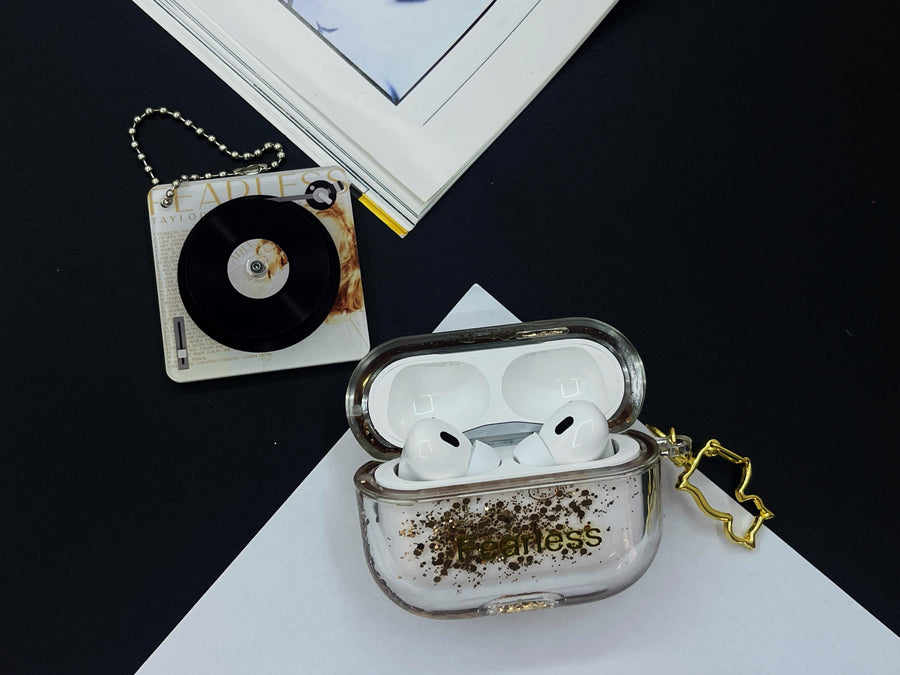 Clear earbud case filled with radiant gold liquid glitter, attached to a gold cat-shaped clip and a miniature vinyl record keychain.