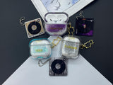 Clear earbud case filled with radiant gold liquid glitter, attached to a gold cat-shaped clip and a miniature vinyl record keychain.
