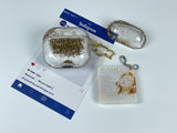 Clear earbud case filled with radiant gold liquid glitter, attached to a gold cat-shaped clip and a miniature vinyl record keychain.