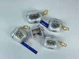 Clear earbud case filled with ghostly silver grayscale liquid glitter, attached to a gold cat-shaped clip and a miniature vinyl record keychain.