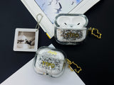 Clear earbud case filled with ghostly silver grayscale liquid glitter, attached to a gold cat-shaped clip and a miniature vinyl record keychain.