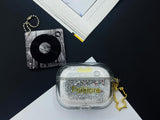 Clear earbud case filled with silver-grey liquid glitter, attached to a gold cat-shaped clip and a miniature vinyl record keychain.
