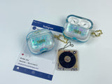 Clear, blue-tinted earbud case filled with iridescent blue liquid glitter, attached to a gold cat-shaped clip and a miniature vinyl record keychain.