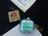 Clear, blue-tinted earbud case filled with iridescent blue liquid glitter, attached to a gold cat-shaped clip and a miniature vinyl record keychain.