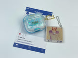 Clear, blue-tinted earbud case filled with iridescent blue liquid glitter, attached to a gold cat-shaped clip and a miniature vinyl record keychain.