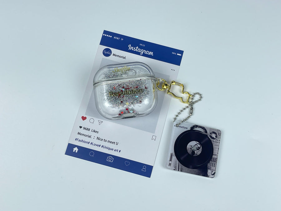 Clear earbud case filled with silver liquid glitter and tiny red stars, attached to a gold cat-shaped clip and a miniature vinyl record keychain.