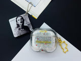 Clear earbud case filled with silver liquid glitter and tiny red stars, attached to a gold cat-shaped clip and a miniature vinyl record keychain.
